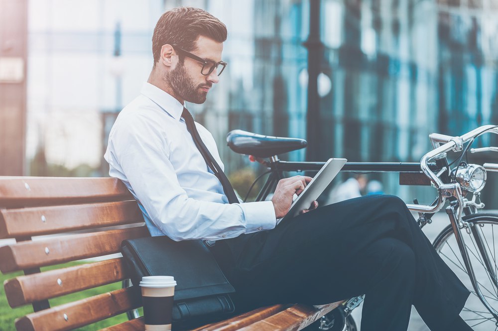 Young Man Sitting On The Bench With Laptop On His Lap